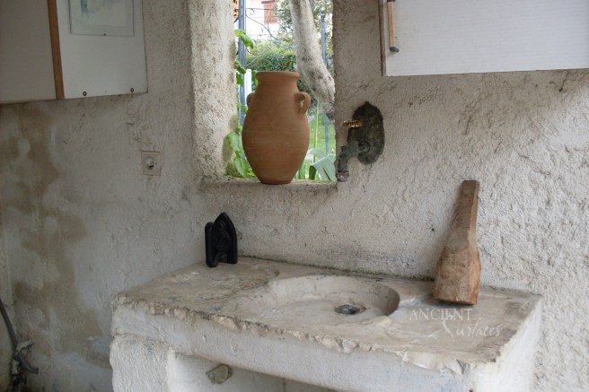 A very old stone block with a shallow sink cutout used as a hand washing sink in a in Tuscan farmhouse.